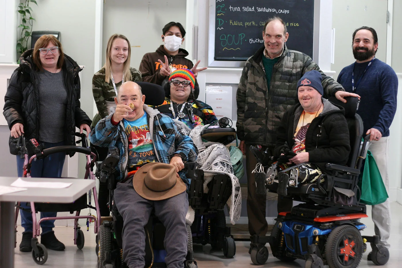 A group gathers for a photo at Hilltop, with people seated in wheelchairs and standing together.