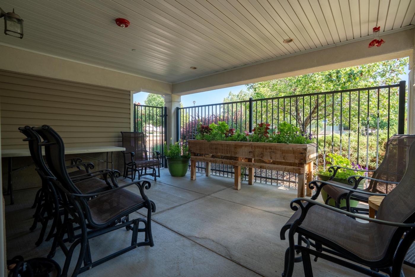 Fenced in patio with chairs and a gardening box