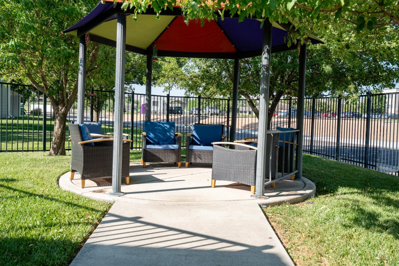 Gazebo with multicolored top in back yard with paved path to patio furniture