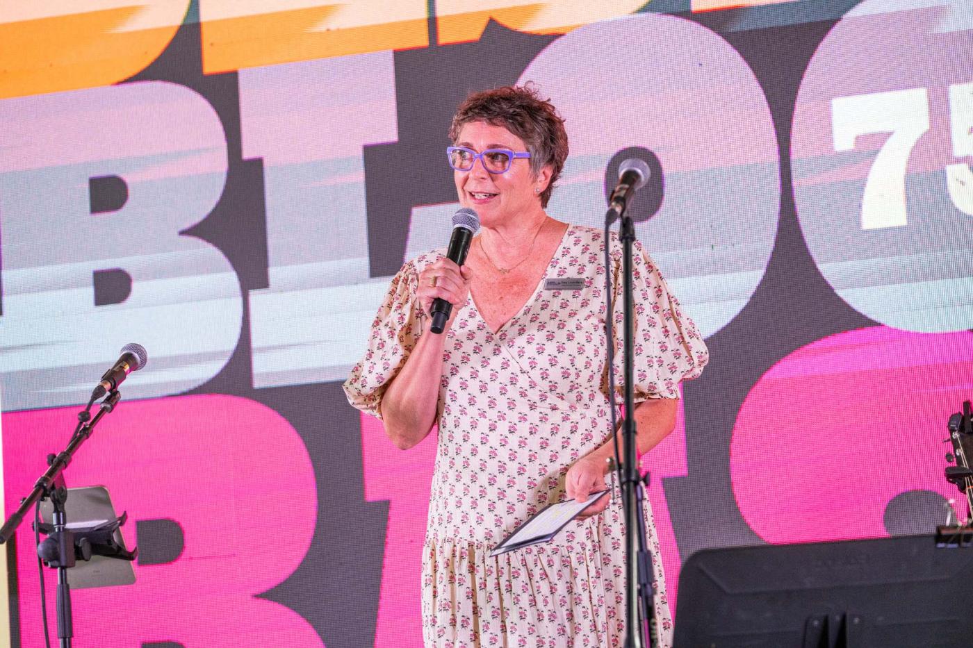 woman with short hair and glasses speaking on stage