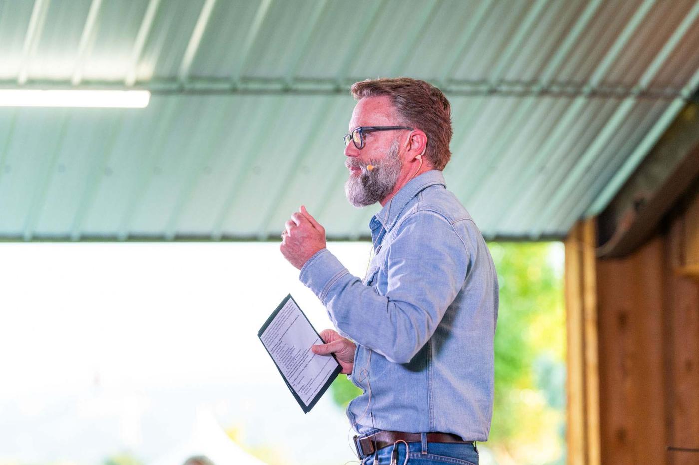 Side profile of man with beard on stage giving speech