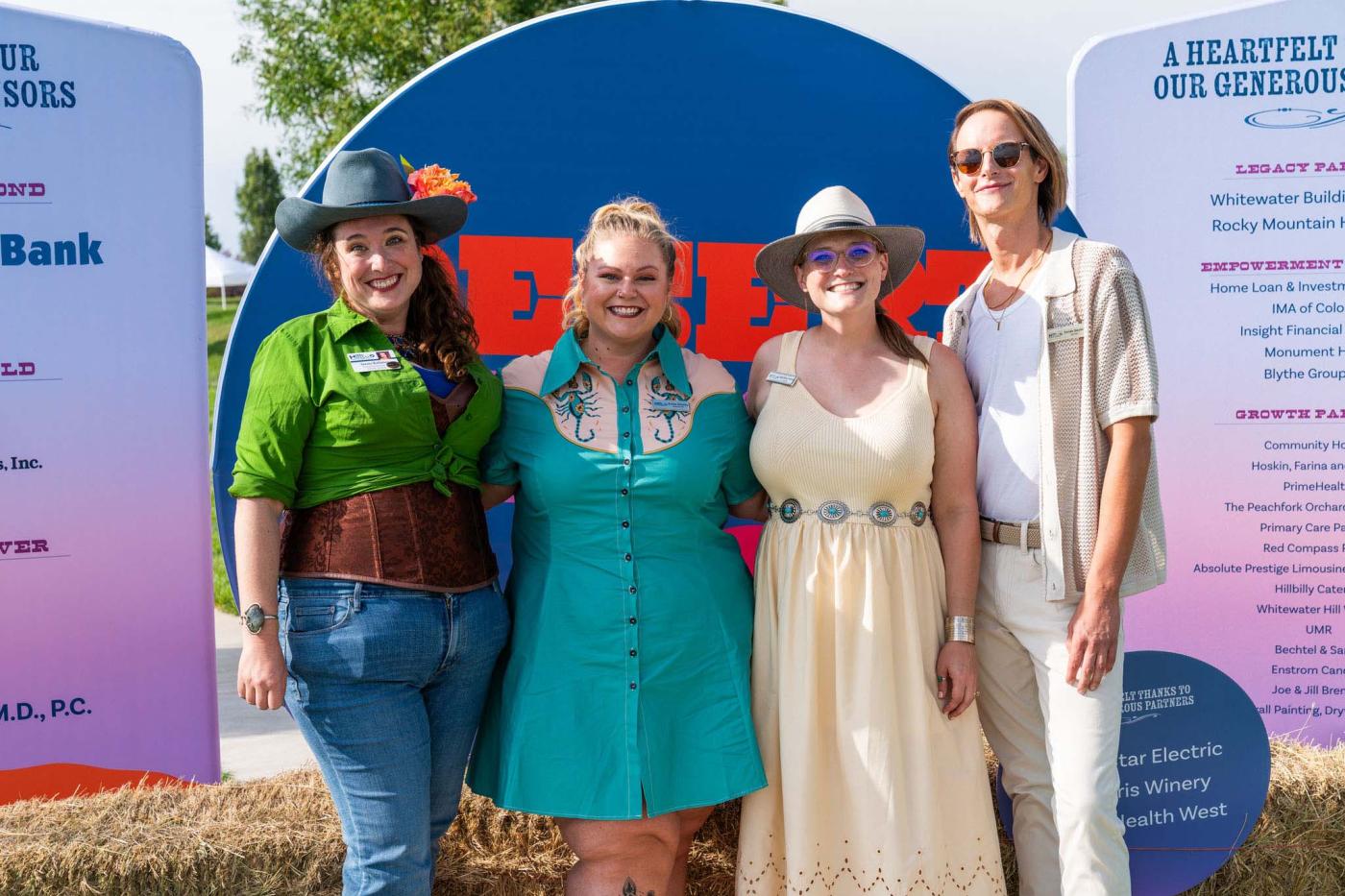 Four registration attendants standing in front of a photo backdrop, smiling