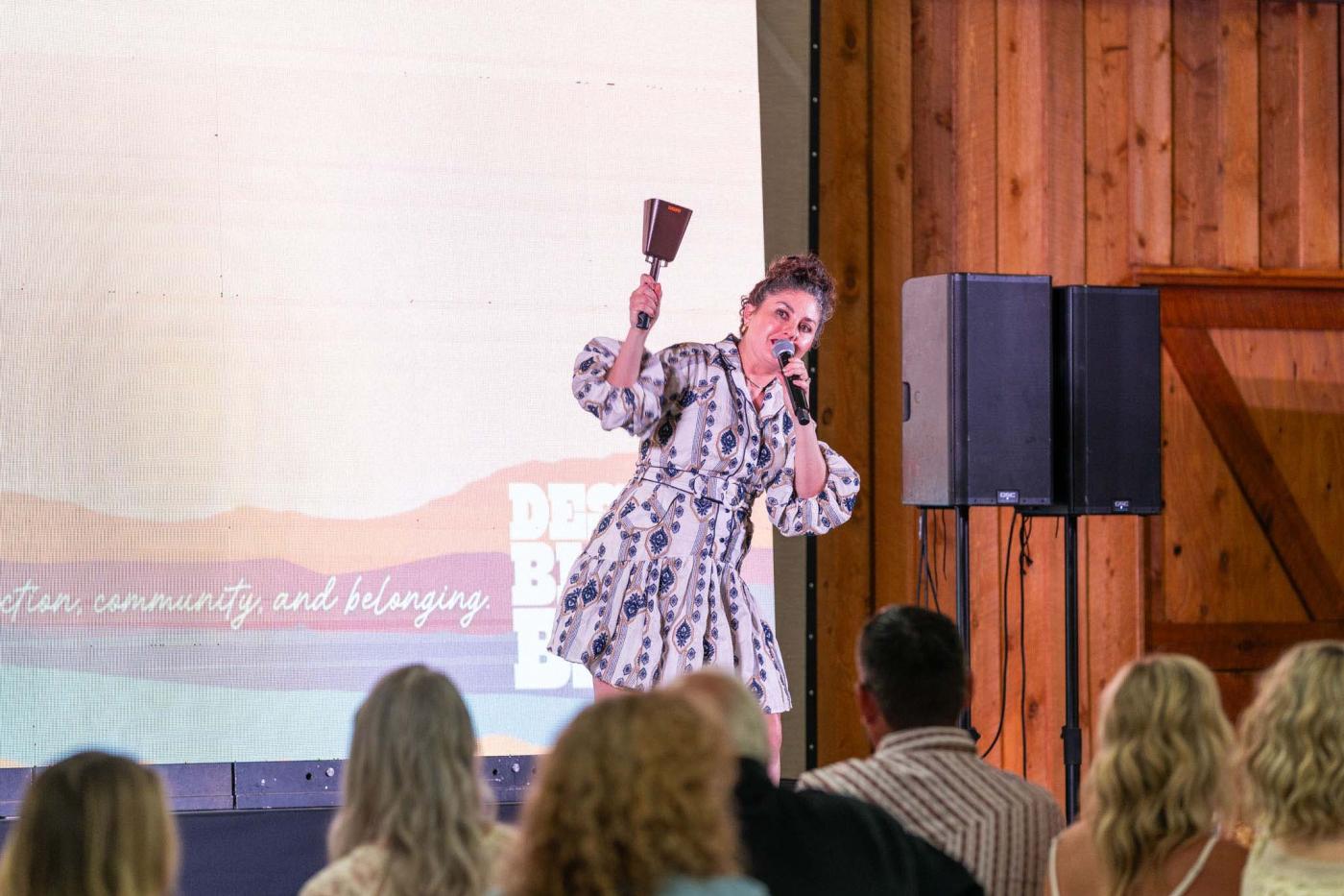 Woman on stage ringing a cowbell