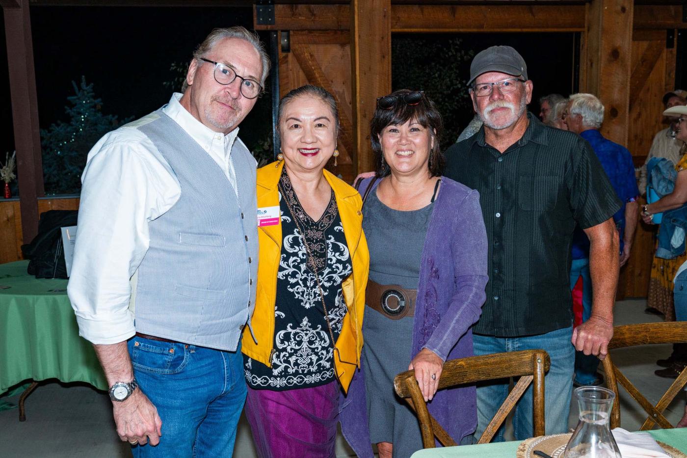 Group of 4 people standing next to table smiling at camera