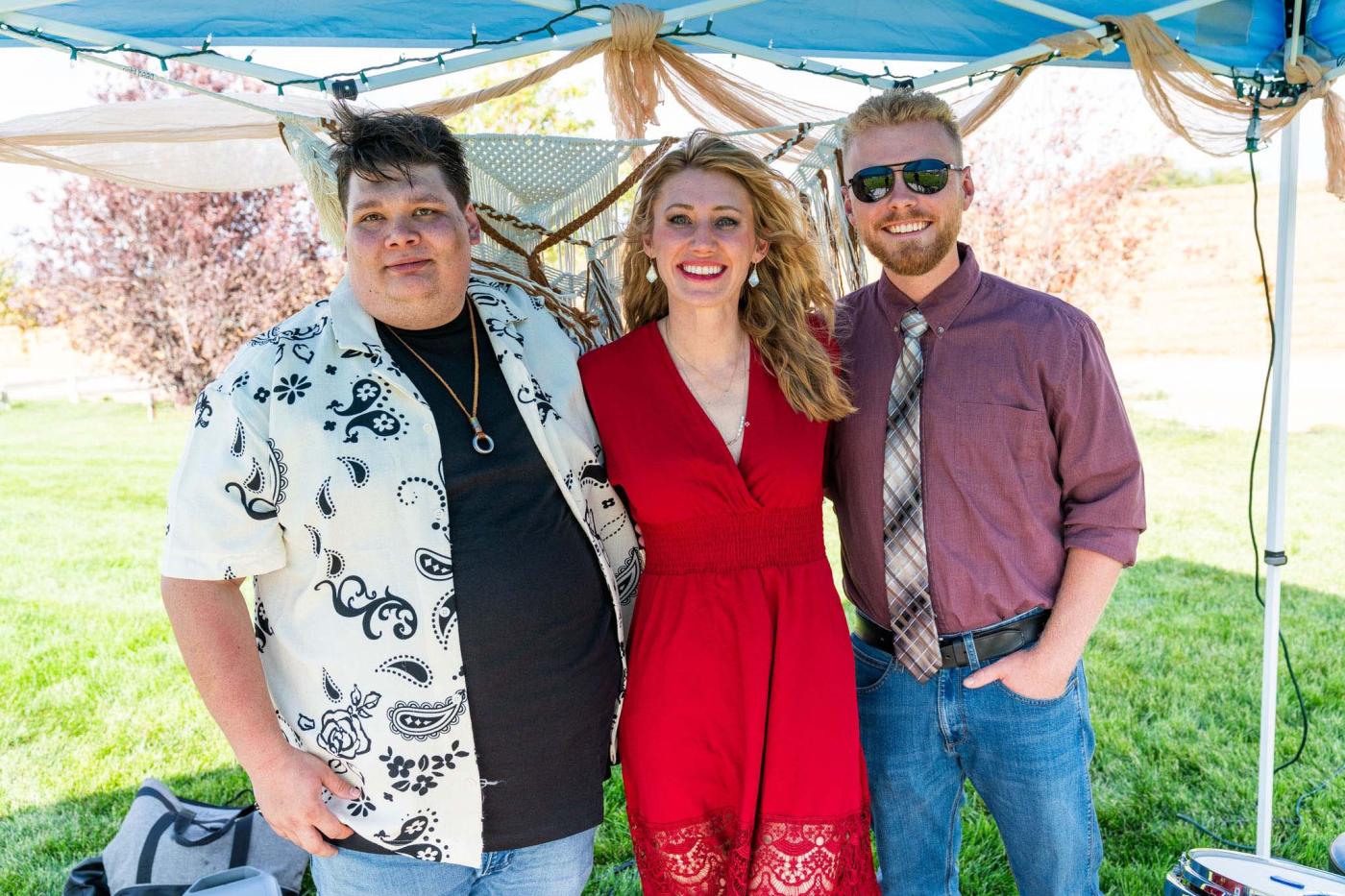 Three people, from the band, standing outside smiling