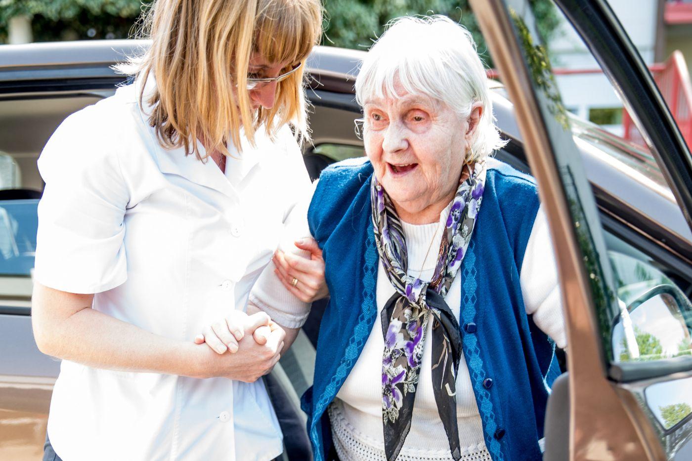 Woman helping elderly woman out of car