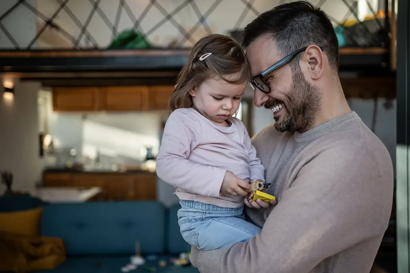 A father gently holding his young child while they play together at home, illustrating the supportive, nurturing parent–child relationships Hilltop’s Early Childhood Services help families build.