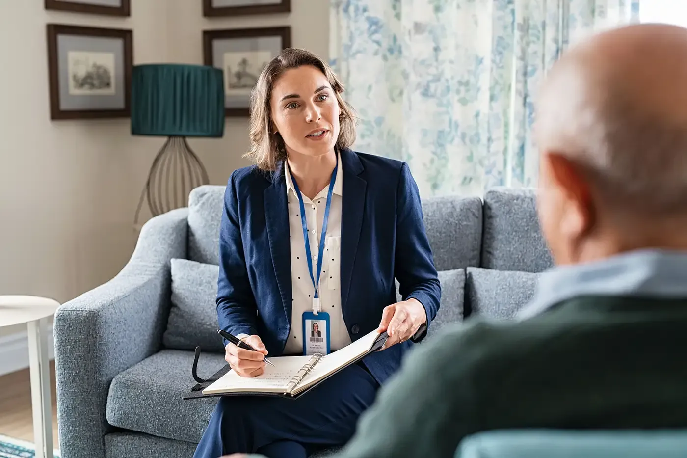 A mental health professional meeting with a client in a comfortable home setting, reflecting the supportive, non-judgmental therapeutic services Hilltop provides for individuals, couples, youth, and families.
