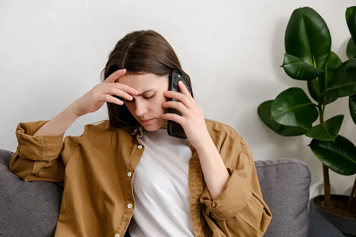 A woman on the phone looking distressed, representing individuals reaching out to Hilltop’s Latimer House for crisis support, safety planning, advocacy, and healing after intimate partner violence or sexual assault.